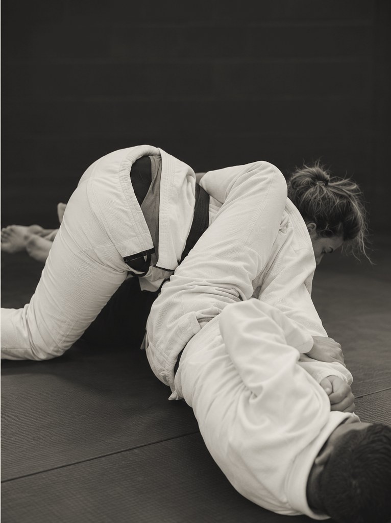 A woman drilling Jiu-Jitsu technique with a training partner on the mat